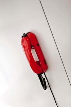 Red phone on a white wall inside a house