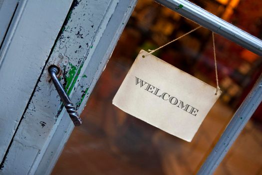 Old door of a vintage shop and welcome sign