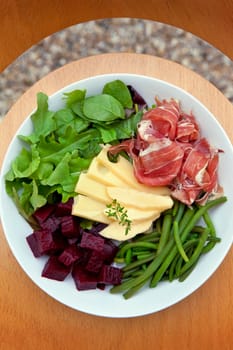 Mixed salad with ham, cheese, beet and beans on a plate