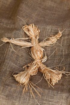 Close up of a raffia doll on a burlap fabric