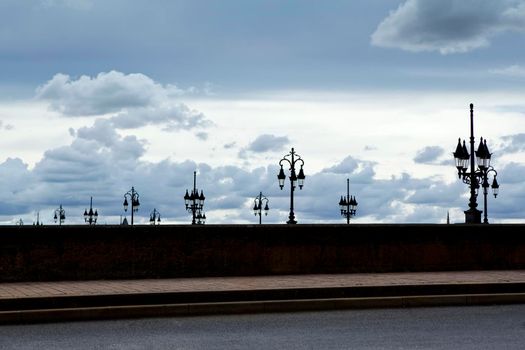 Many street lamps and stone wall on an old bridge of Bordeaux, France