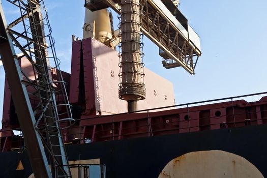 Loading grain into holds of sea cargo vessel in seaport from silos of grain storage. Bunkering of dry cargo ship with grain.