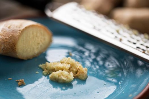 Ginger root and minced ginger on plate with shredder.