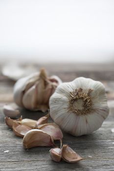 Garlic heads and cloves on wooden table with copy space.