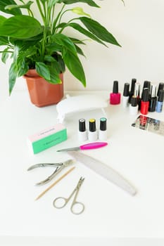 The concept of the workspace of the master of the nail salon. Top view of manicure tools on a white table. Cosmetic procedures and hand care