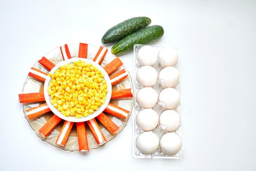 a cold dish of various mixtures of raw or cooked vegetables, usually seasoned with oil, vinegar, or other dressing. A set for a delicious healthy salad. Cucumbers, eggs, corn, crab sticks.