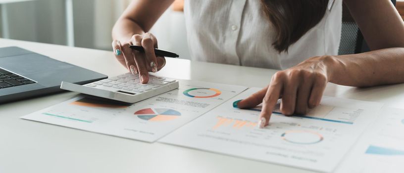 business woman or accountant working on calculator to calculate business data, accountancy document and laptop computer at office, business concept.