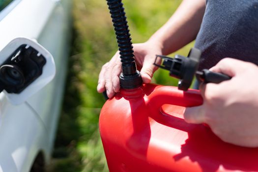 The driver refuels the empty tank of the car from a red canister on the side of the road. Fuel problem, force majeure