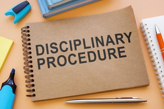 A Notebook about disciplinary procedure with papers on the table.