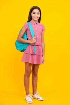 Schoolgirl in school uniform with school bag. Schoolchild, teen student hold backpack on yellow isolated background