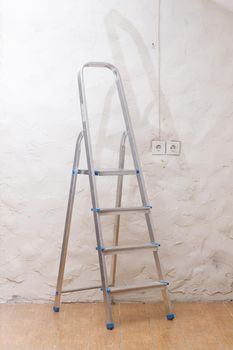 A simple stepladder stands on the floor in an empty home room.