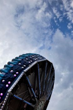 Ride turning in a fairground, cloudy sky on background