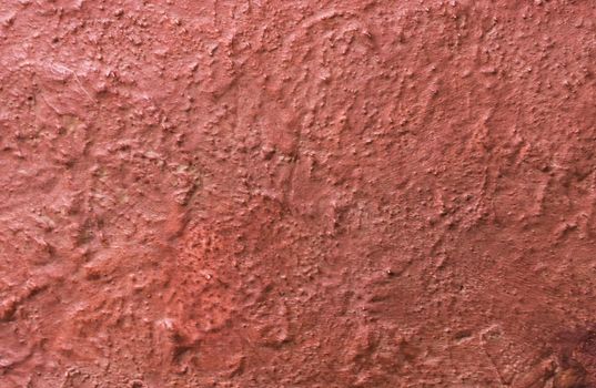 Background for design with copy space. Fragment of a wall with rough relief plaster of red color.