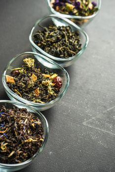Different types of tea, green tea, peony and ginger tea, rose bud and wild flowers tea on dark wooden background with copyspace