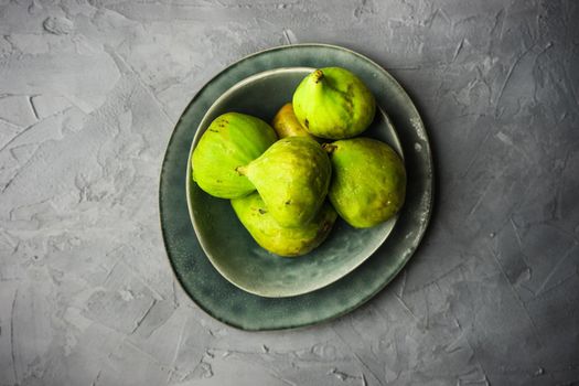 Organic fig tree fruits on the vintage plate on concrete background with copyspace