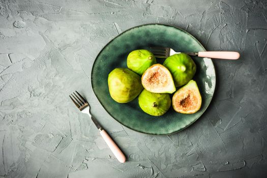 Organic fig tree fruits on the vintage plate on concrete background with copyspace