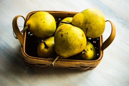 Organic pear fruits on the vintage plate on wooden background with copyspace