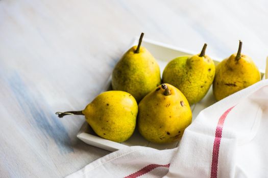Organic pear fruits on the vintage plate on wooden background with copyspace