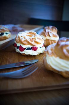 Dessert profitrole with vanila cream and ripe fresh berries like a strawberry, bilbery and rapsberry