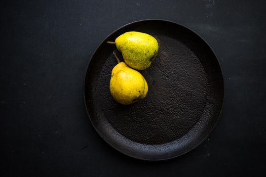 Organic pear fruits on the vintage plate on wooden background with copyspace