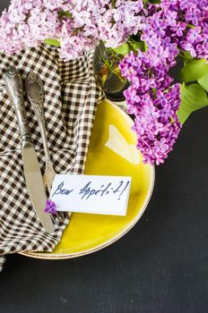 Spring table setting with bright lilac flowers on rustic background with copyspace