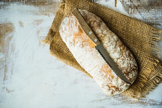 Fresh baked italian bread - ciabatta  on rustic table with napkin