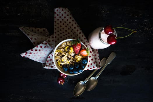 Healthy breakfast with oatmeals and organic berries - blueberry and strawberry on dark wooden table with copyspace