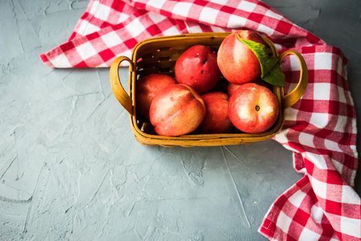 Ripe nectarine fruits in a busket on grey concrete table with copyspace