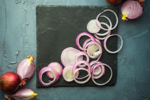 Organic food concept with red onion on dark cutting board with copyspace