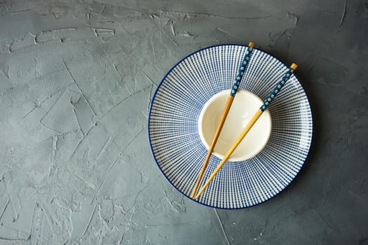 Table setting with flatware and chopsticks o concrete background