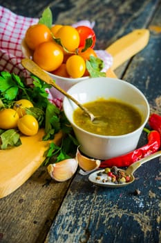 Traditional georgian sauce green tkemali with raw products on rustic wooden table