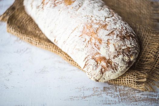 Fresh baked italian bread - ciabatta  on rustic table with napkin