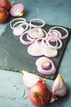 Organic food concept with red onion on dark cutting board with copyspace