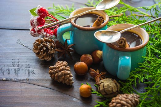 Mug of coffee with spices - cinnamon sticks and anise star with Christmas decor on dark wooden table with copyspace