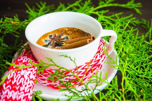 Mug of coffee with spices - cinnamon sticks and anise star with Christmas decor on dark wooden table with copyspace