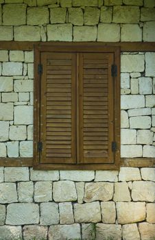 Beautiful brick house with shutters on a window and tropical garden