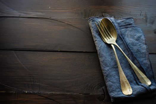 Rustic table setting with bright napkin nd silverware on dark wooden table