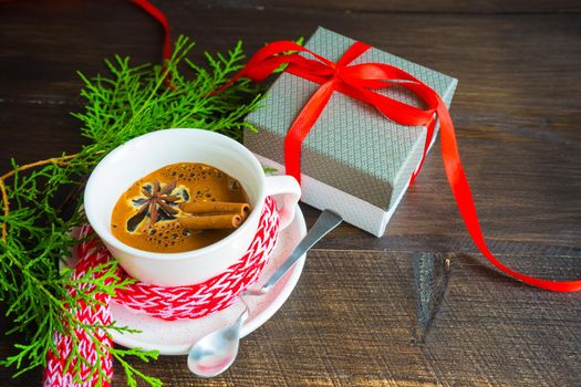Mug of coffee with spices - cinnamon sticks and anise star with Christmas decor on dark wooden table with copyspace