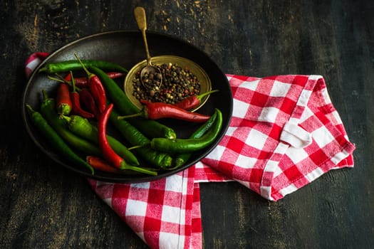 Organic chilli peppers on a pan on dark wooden background with copyspace