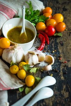 Traditional georgian sauce green tkemali with raw products on rustic wooden table