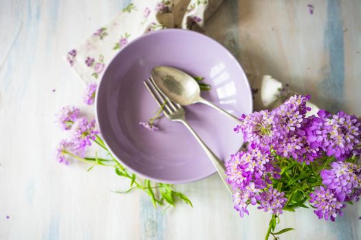Summertime floral table setting with bright purple flowers with copysace