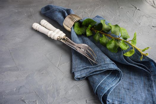 Rustic table setting with vintage ceramic plates and branch of ivy plant on dark old wooden table with copyspace