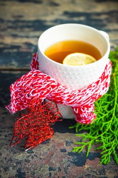 Cup of tea with lemon and cinnamon spice and Christmas decoration on rustic wooden table