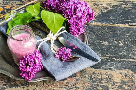 Spring table setting with bright lilac flowers on rustic background with copyspace
