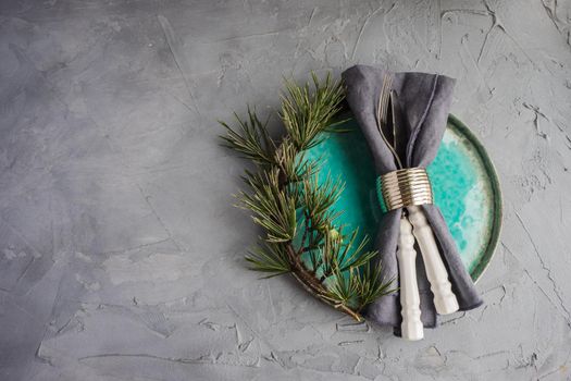 Rustic table setting with vintage tableware  and branch of Christmas tree  on grey concrete table with copyspace