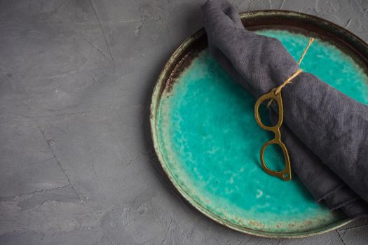 Rustic table setting with vintage tableware  and glasses napkin ring on grey concrete table with copyspace
