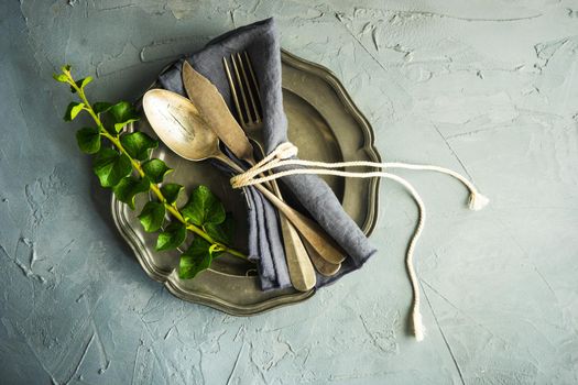 Rustic table setting with vintage ceramic plates and branch of ivy plant on dark old wooden table with copyspace