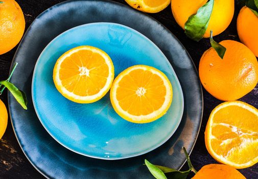 Orange fruits with clises on bright color ceramic plates on dark rustic wooden table
