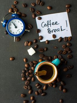 Mug with black coffee, coffee beans, milk and sugar on dark wooden table