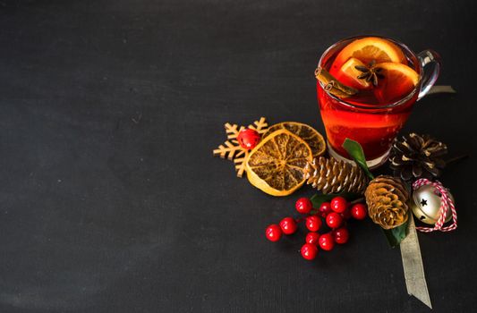 Glass od spiced mulled wine and Christmas decoration on black table with copyspace